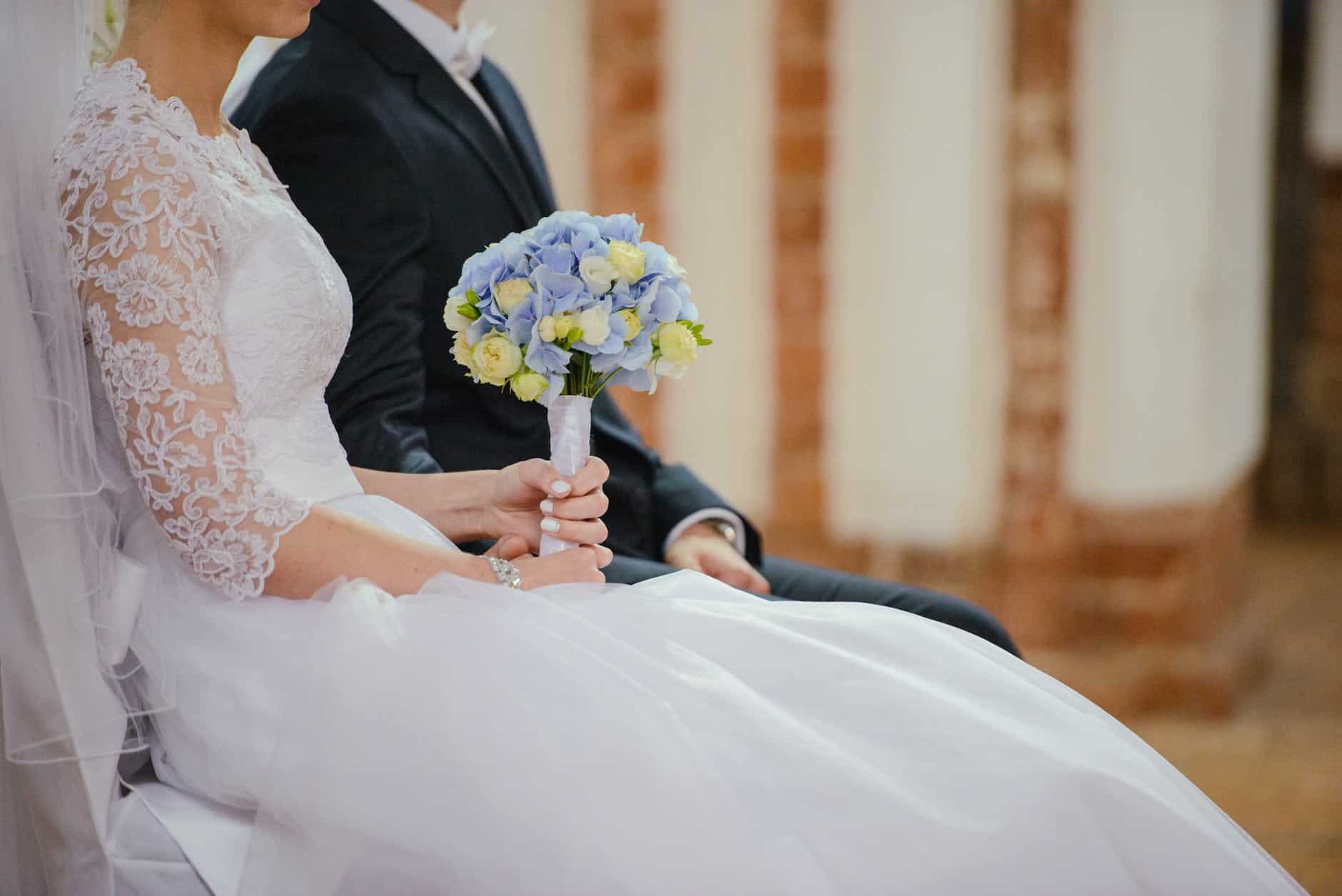 unrecognizable young newlyweds sitting together during wedding celebration