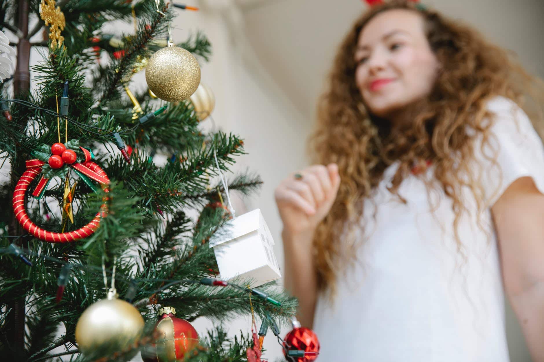 young woman standing near christmas tree decorated with baubles